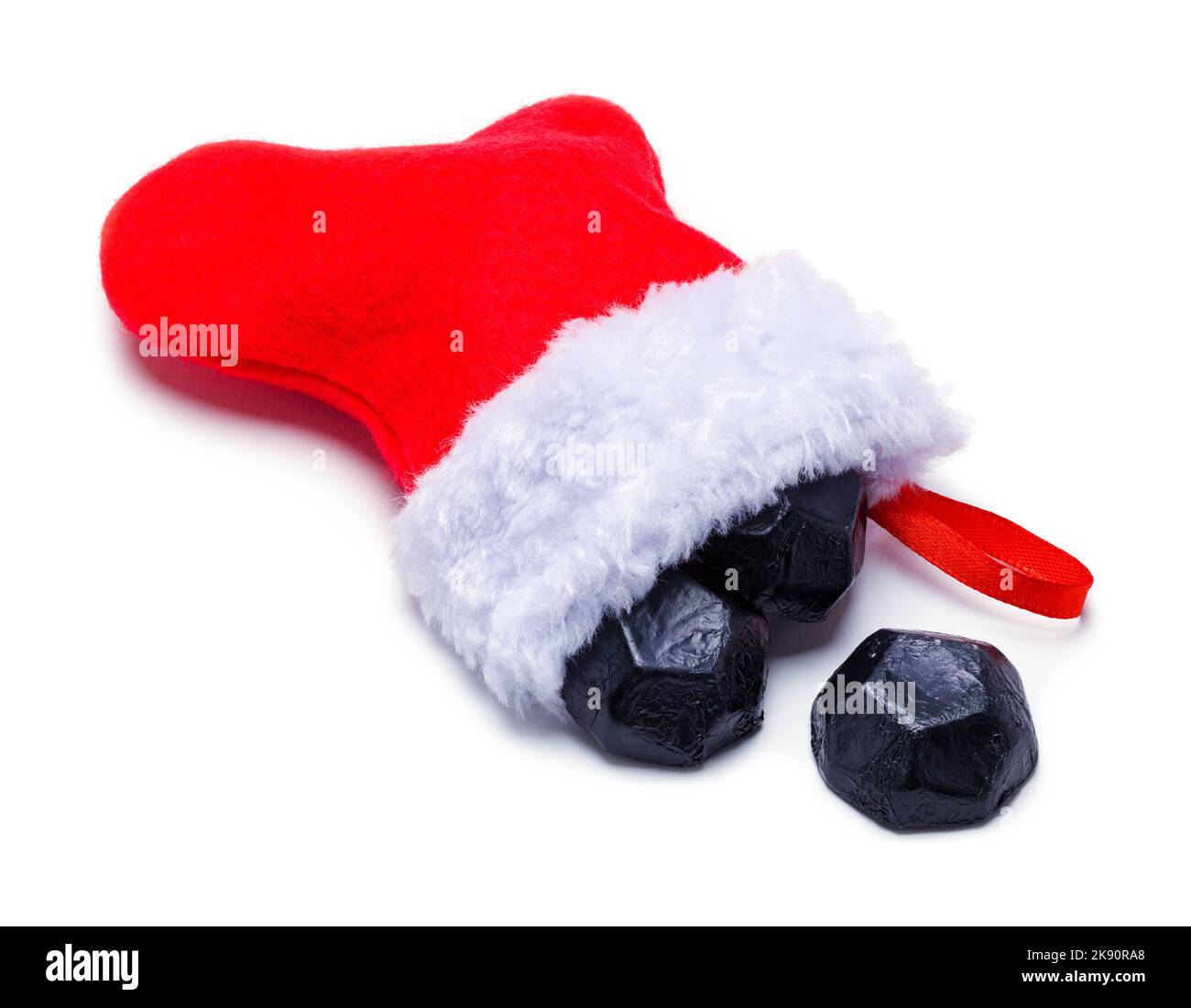 Kleiner roter Weihnachtsstrumpf mit Kohle-Süßigkeiten auf Weiß. Stockfoto