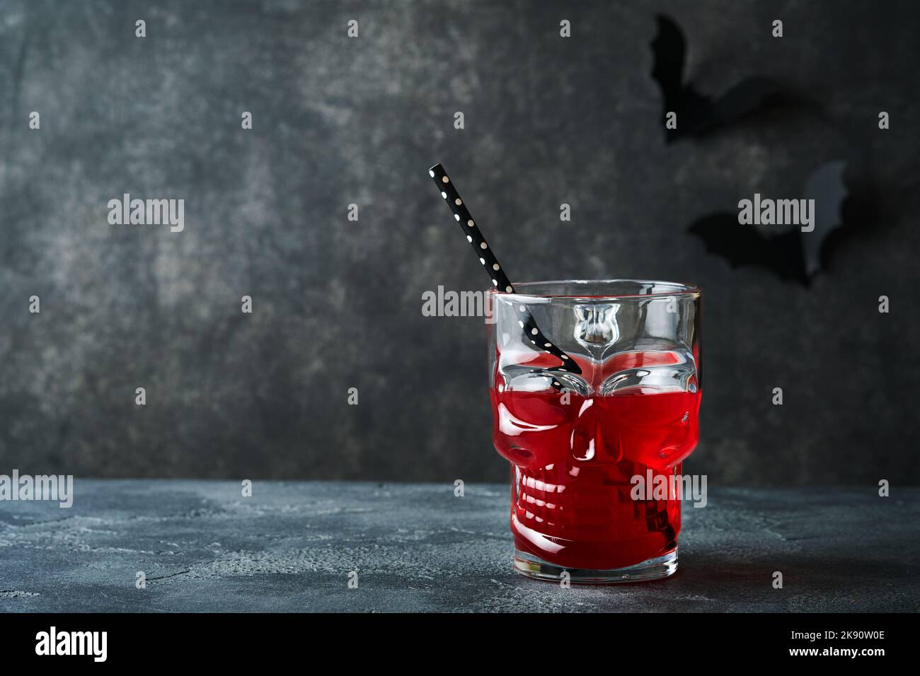 Blutiger Halloween-Cocktail. Blutig roter Cocktailglas-Becher für Halloween und Flaschenform Totenkopf auf dunklen Hintergründen. Halloween-Party mit Süßigkeiten Augen, Stockfoto