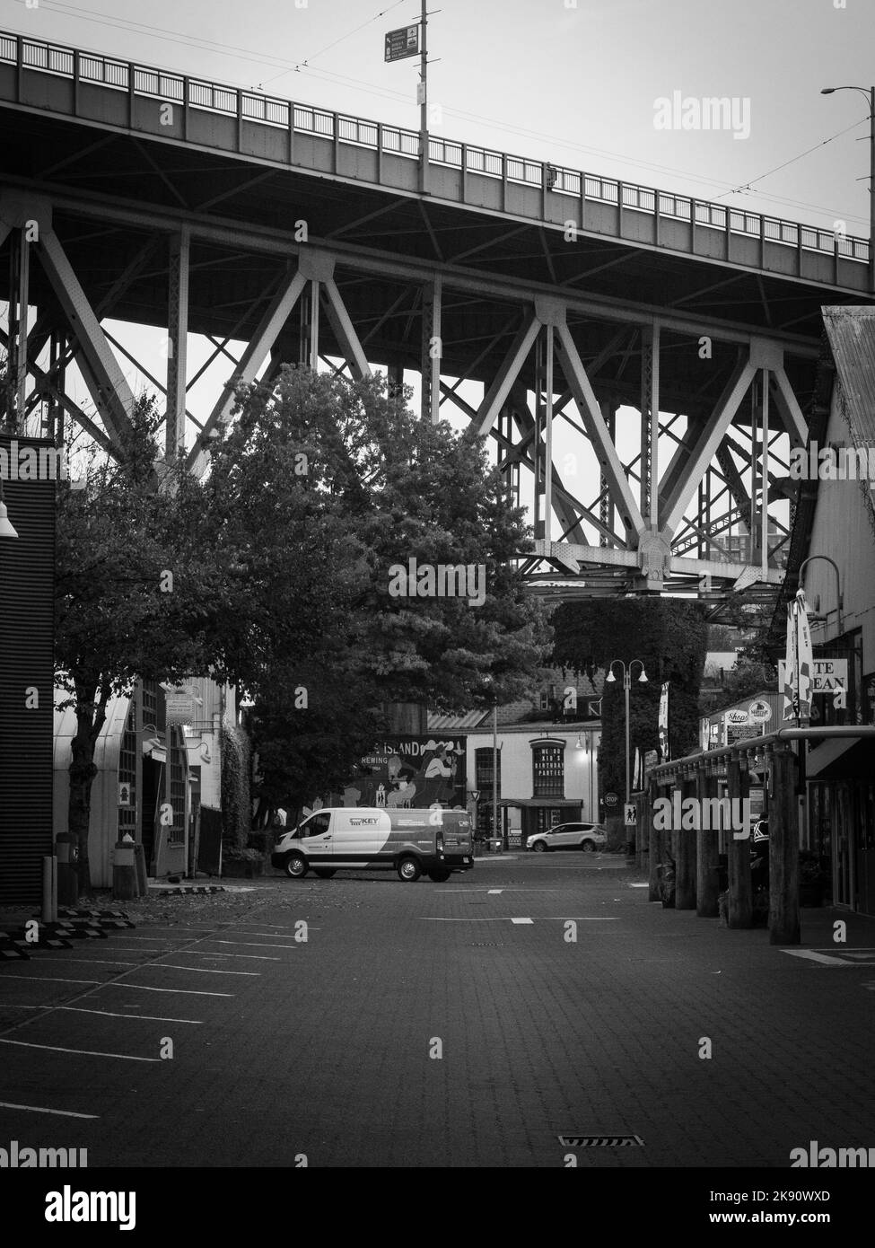 Eine vertikale Graustufe einer leeren Straße mit einer großen Brücke darauf in Vancouver, Kanada Stockfoto