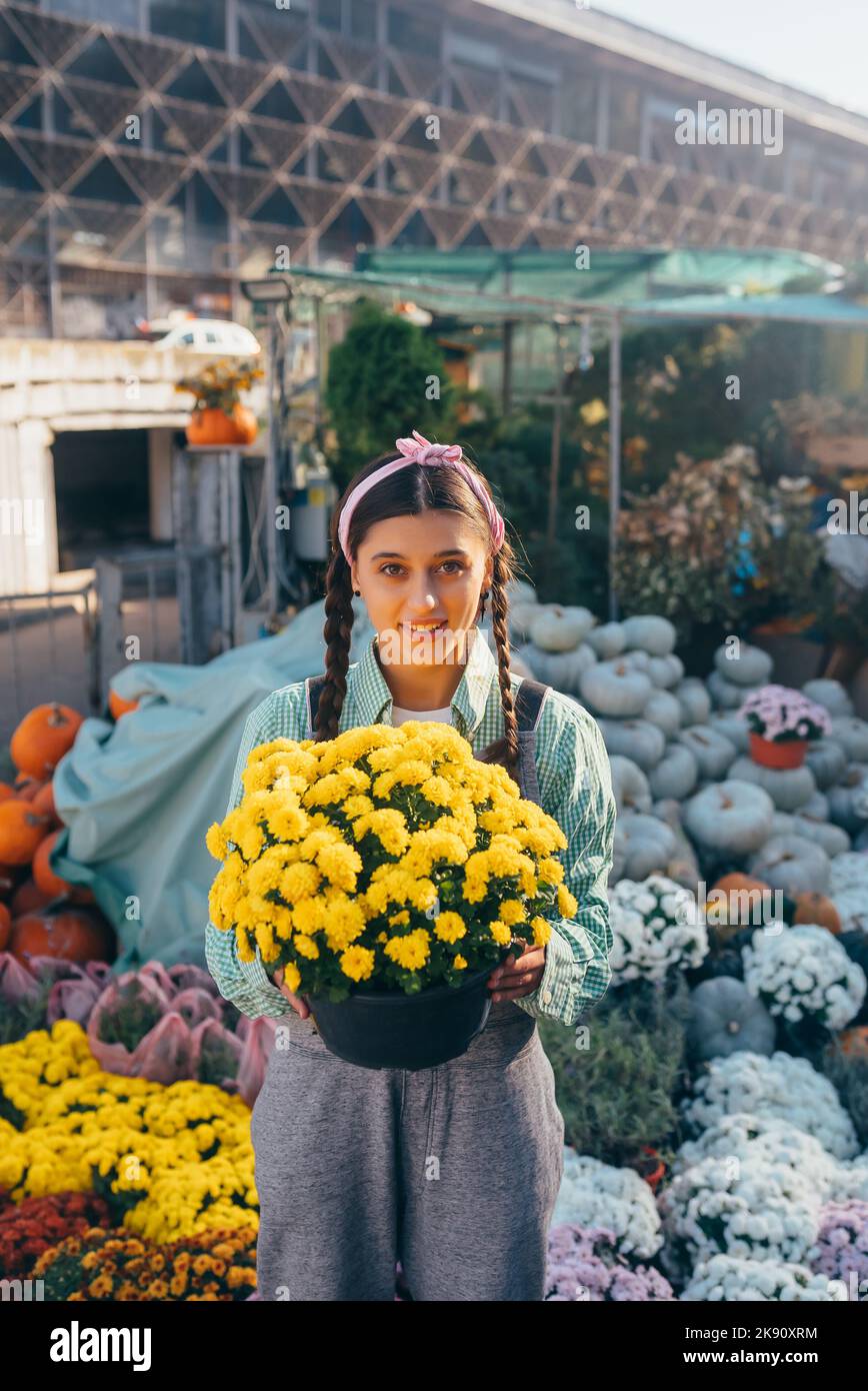 Frau hält dekorative Blume in Blumentopf auf dem Markt. Stockfoto