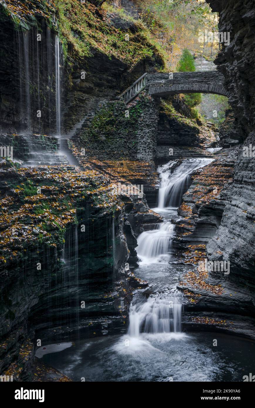 Die vertikale Langzeitbelichtung szenischer Blick auf die Wasserfälle fallen unter einer Kaskade unter einer historischen Brücke Stockfoto