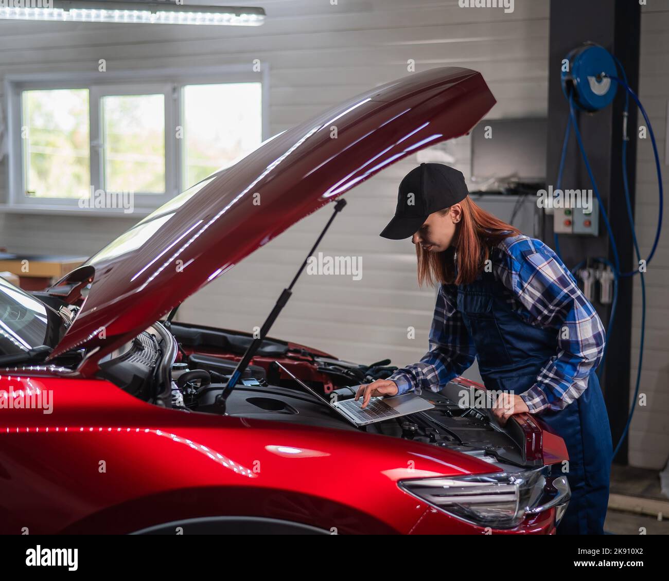 Frau Auto Mechaniker tun Motordiagnose mit Laptop. Stockfoto