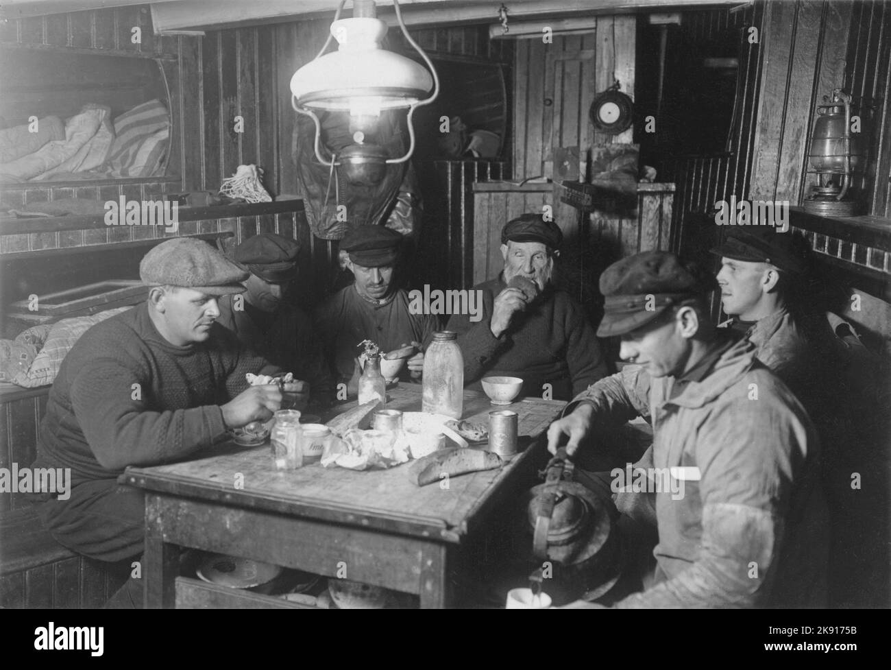 In der 1930s. Das Innere eines kommerziellen Fischerbootes und die Seeleute, die unter Deck etwas zu essen hatten. Eine Paraffin-Lampe vom seiling beleuchtet den schmalen Wohnbereich, in dem das Schlafen und Essen stattfindet. Schweden 1938. Stockfoto