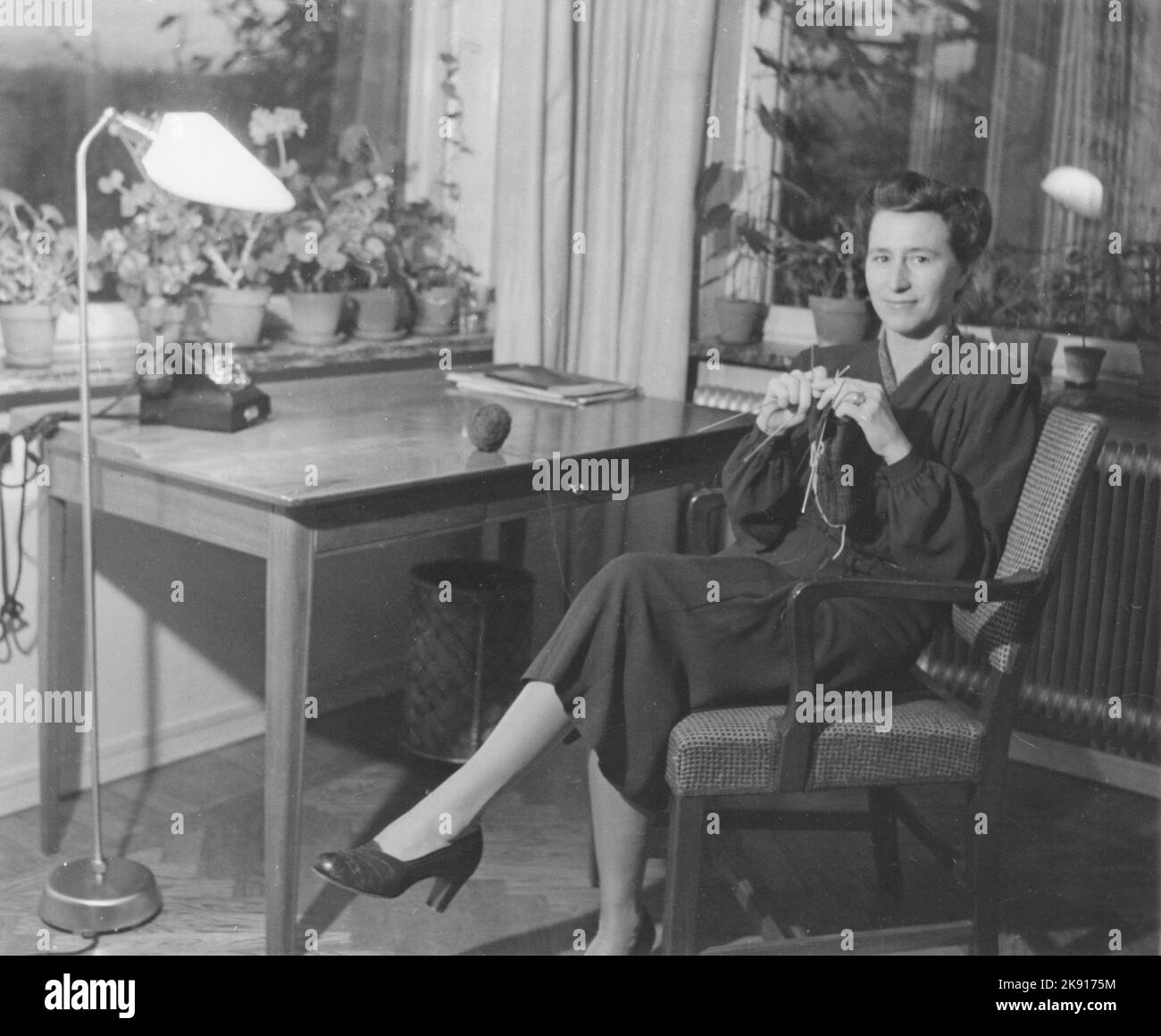 Frau in den 1940s. Eine junge dunkelhaarige Frau zu Hause, die etwas strickt, wenn sie auf dem Stuhl an ihrem Schreibtisch sitzt. Schweden 1948 Stockfoto