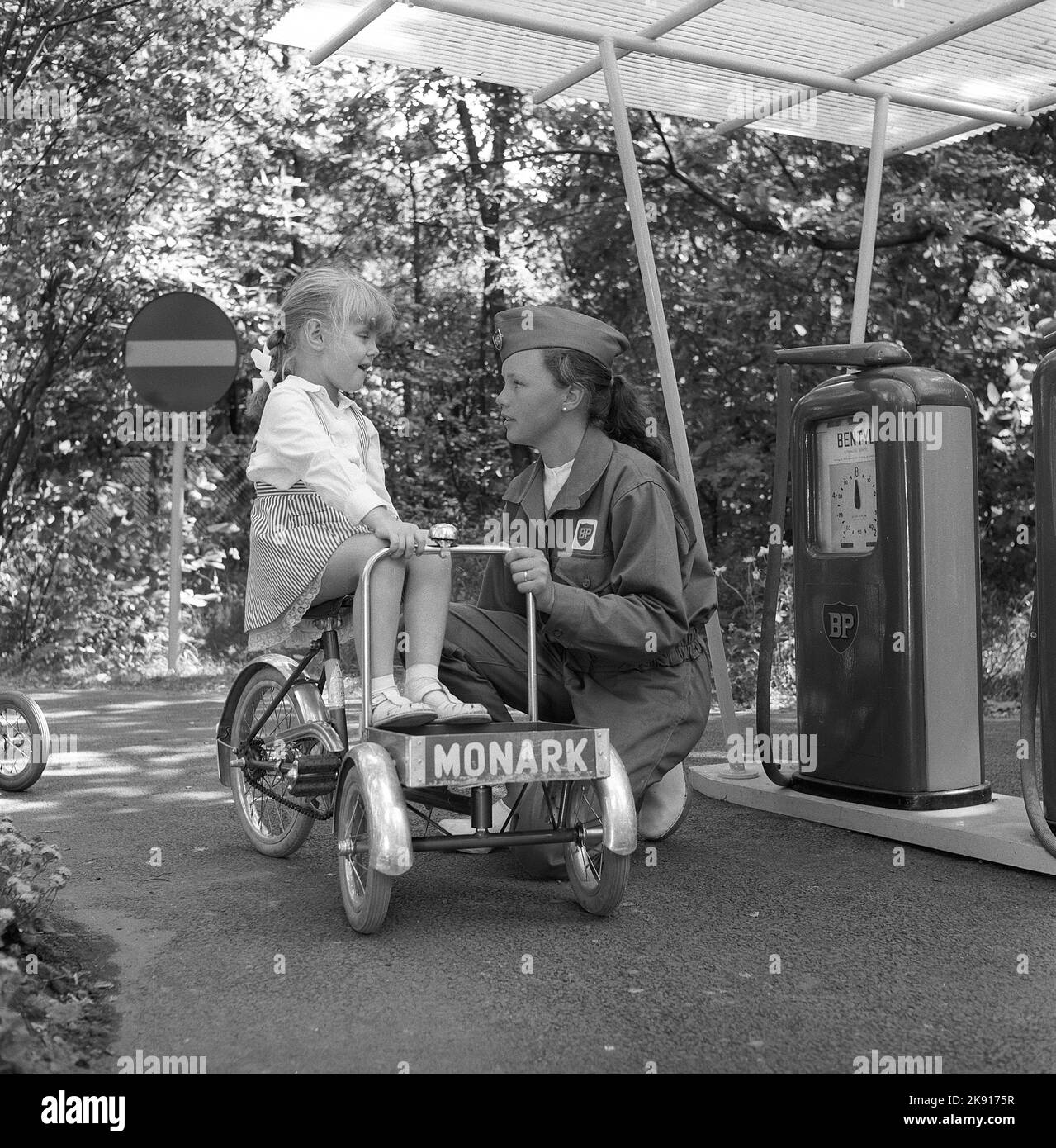In der 1950s. Ein Mädchen auf einem Dreirad nimmt an einer Kinderverkehrsschule Teil, wo die Kinder lernen, sich im Verkehr zu verhalten. Straßen und Häuser sind kleiner als üblich und sogar die Tankstelle ist da, wo ein Service-Mitarbeiter die Kinder betreut und bei der Make-believe-true-Übung mitspielt. Das Jahr ist 1958. Schweden Ref. CV79 Stockfoto