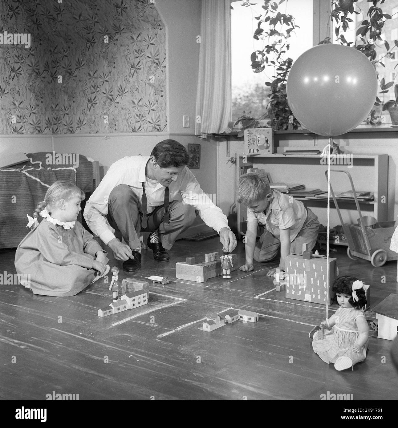 In der 1950s. Ein Mann mit zwei Kindern spielt auf dem Boden mit Autos und Häusern, macht Straßen und erzieht die Kinder vielleicht im Straßenverkehr. Das Jahr ist 1958. Schweden Ref. CV79 Stockfoto
