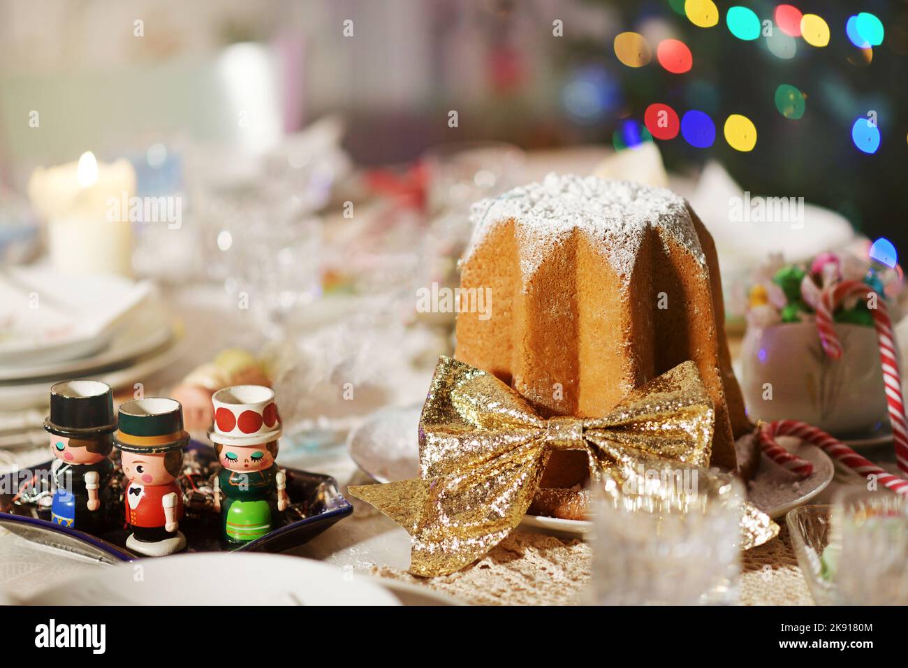 Dekorierter italienischer Pandoro-Weihnachtskuchen mit goldenem Band auf einem Tisch mit verschiedenen festlichen Weihnachtsdekorationen zur Feier der Weihnachtszeit Stockfoto