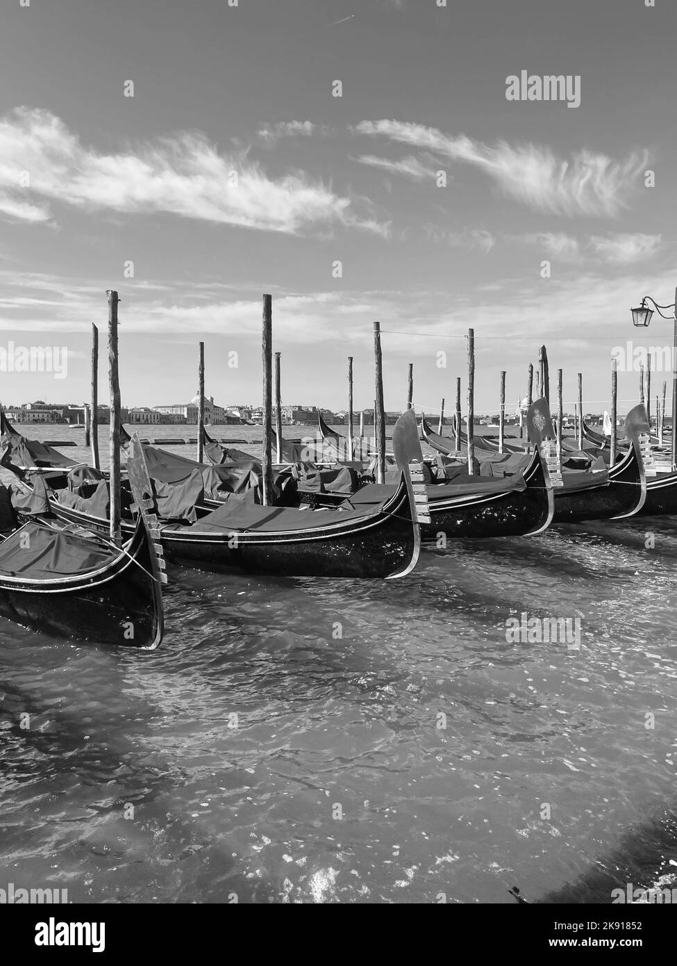 Eine vertikale Schwarz-Weiß-Aufnahme einer Gruppe von Gondeln im Meer bei Venedig Stockfoto