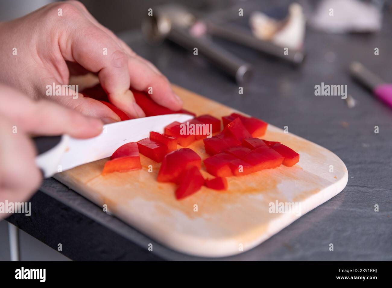 Bild von Frauenhänden, die roten Pfeffer schneiden Stockfoto