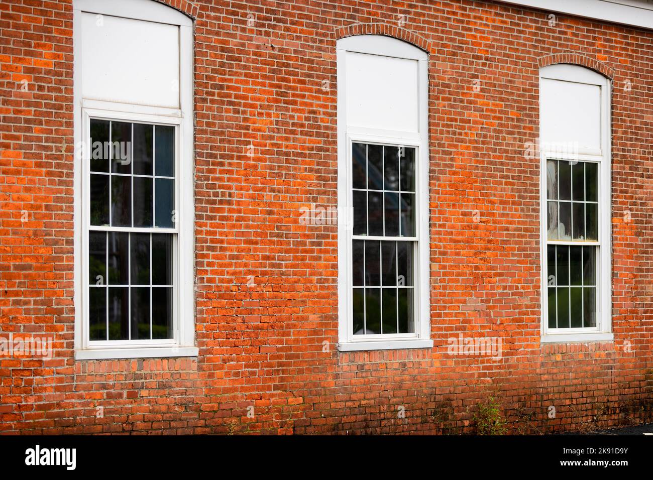 Nahaufnahme einer Außenwand eines Backsteingebäudes mit weiß gerahmten Fenstern. Stockfoto