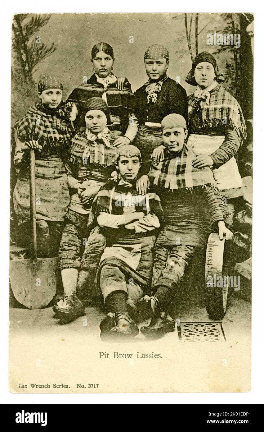 Originalpostkarte von Pit Brow 'Lassies' aus der viktorianischen Zeit, in Arbeitskleidung, einschließlich Hosen mit Werkzeugen des Handels - Schaufeln und Siebe, Arbeitswerkzeuge. Wigan, Lancashire, Großbritannien, veröffentlicht am 1906. Februar, aber fotografiert um 1900. Stockfoto