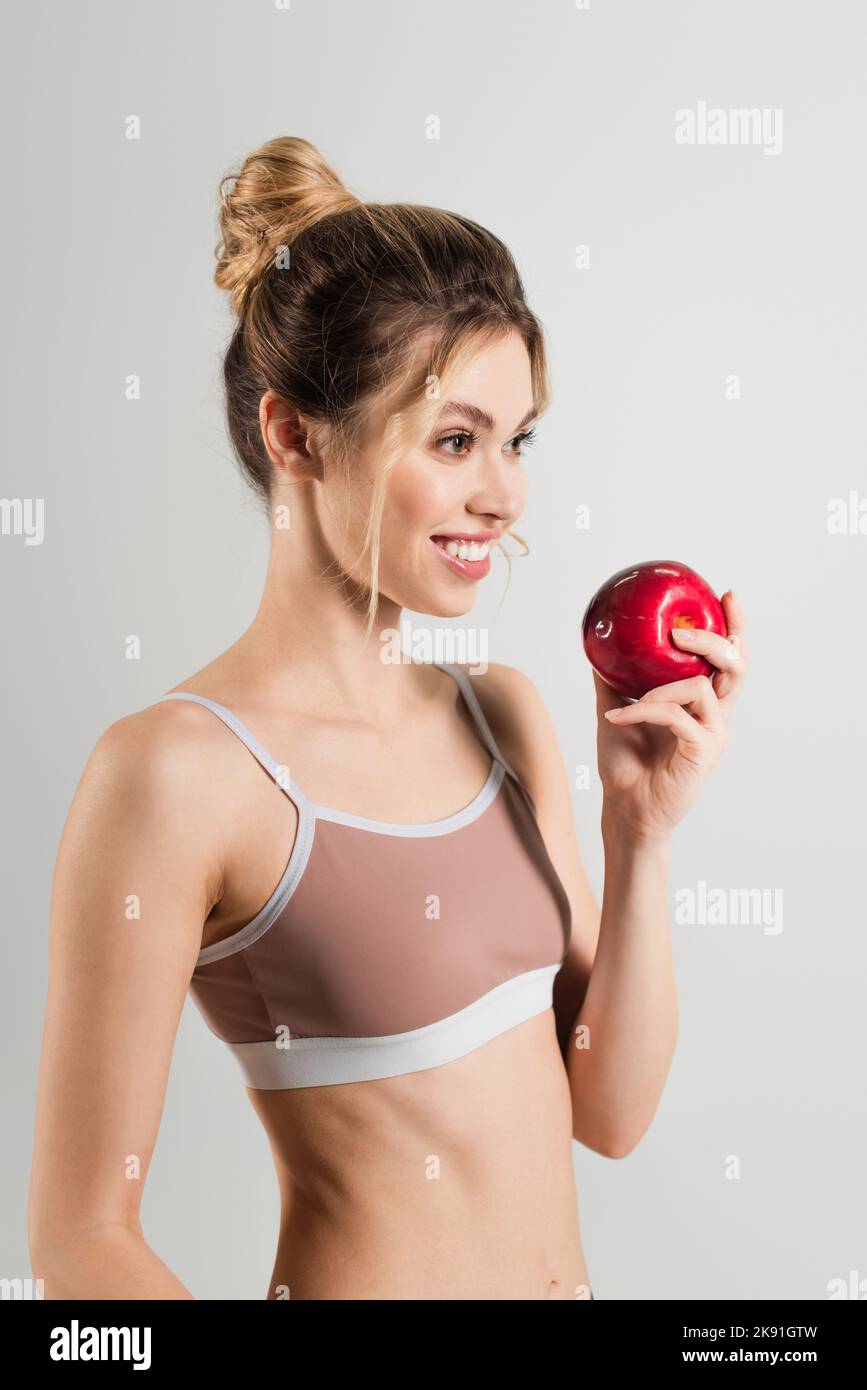 Fröhlich fit Frau mit natürlichen Make-up und frischen Apfel suchen weg isoliert auf grau Stockfoto