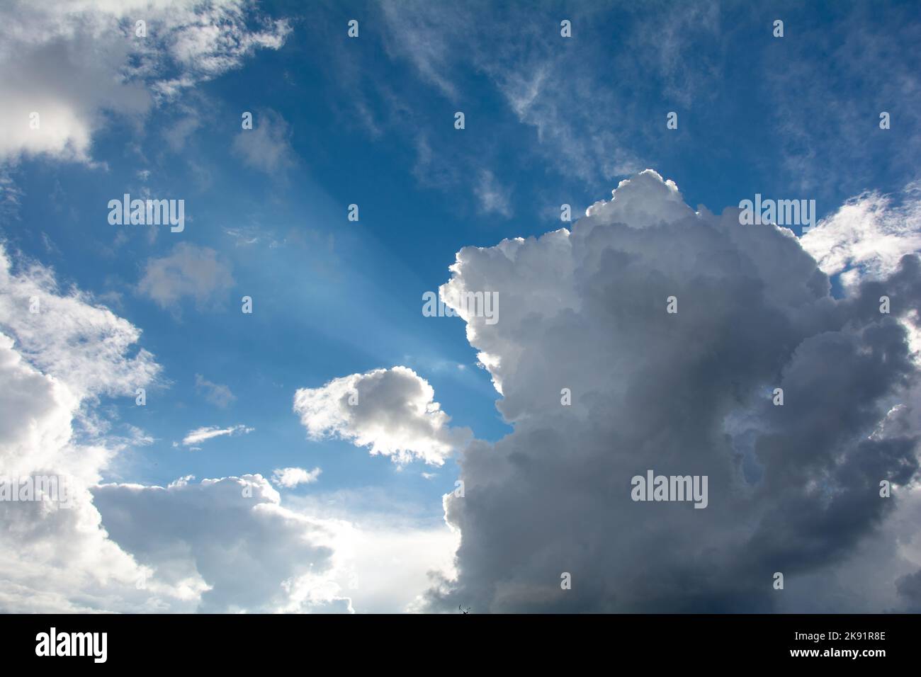 Helle und dunkle Wolken am blauen Himmel mit Sonnenstrahlen Stockfoto