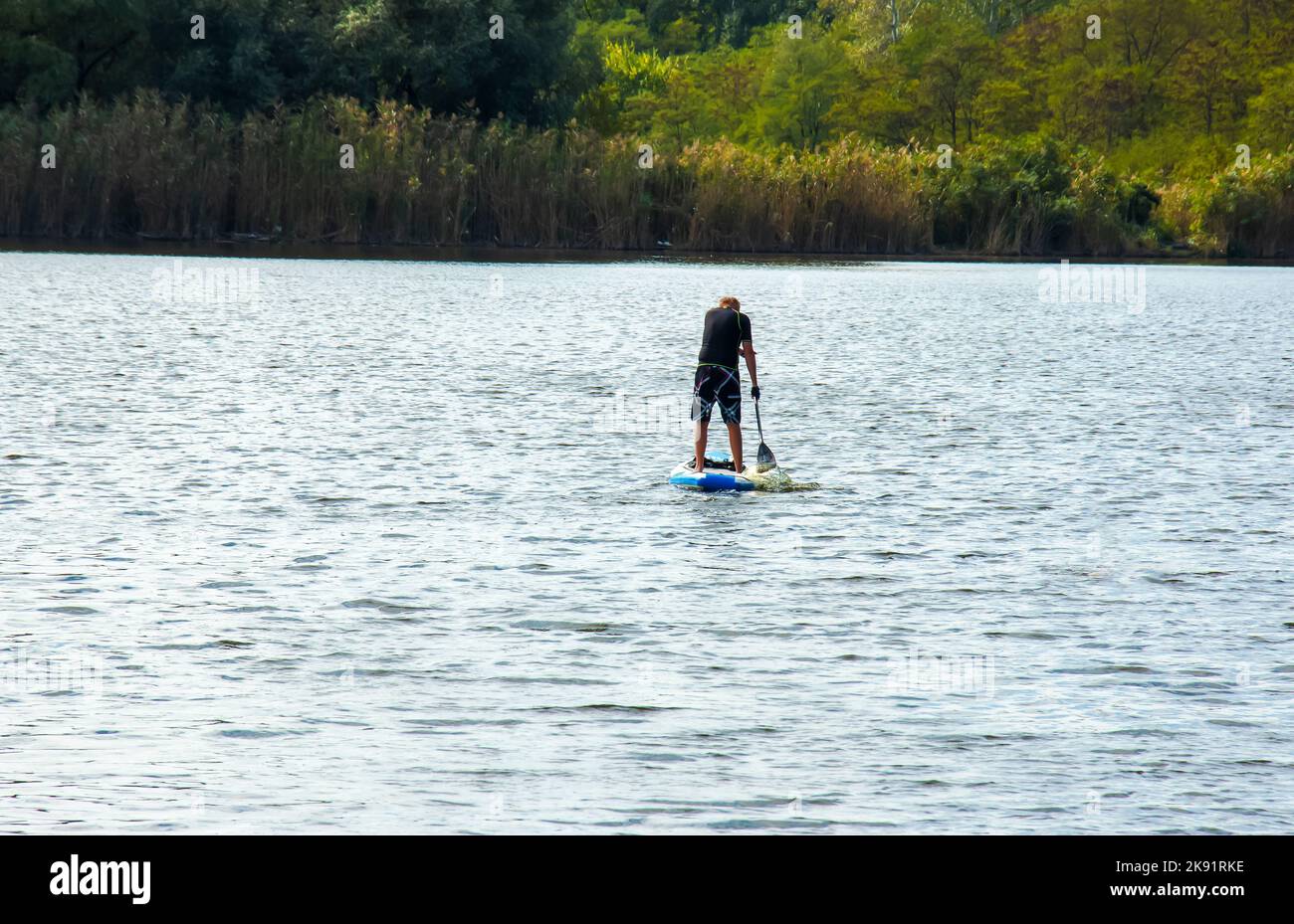 Dnipro, Ukraine - 09.08.2022: Ein Sportler der fortgeschrittenen Jahre fährt auf einem Saphirbrett auf dem Fluss. Fotosatz. Wasseraktivitäten in der Stadt. Stockfoto