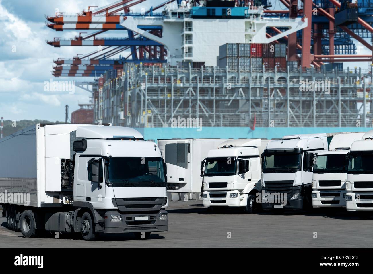 LKW im internationalen Seehafen vor dem Hintergrund eines mit Containern beladenen Schiffes. Internationales Handels- und Logistikkonzept Stockfoto