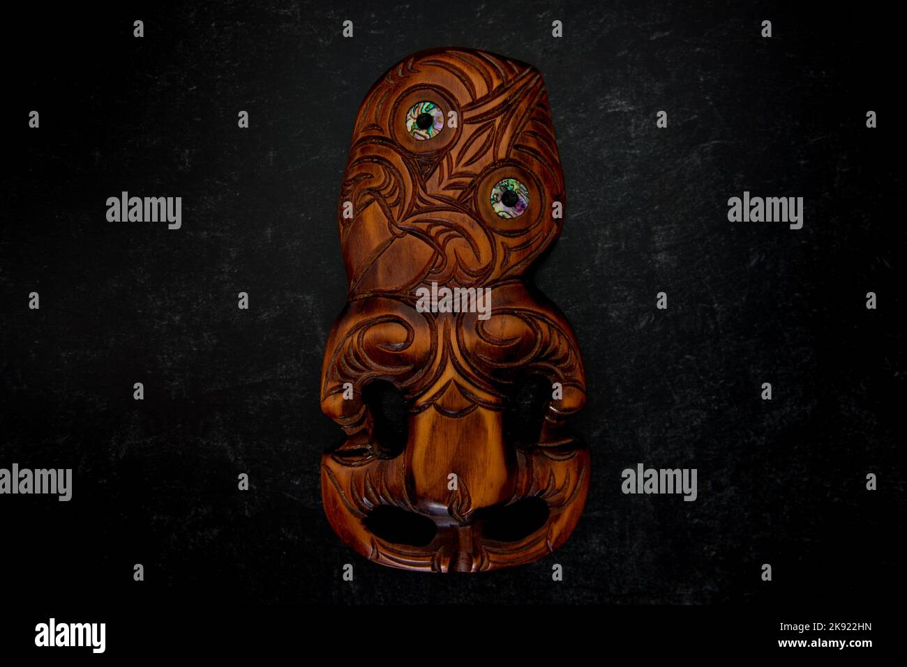 Maori Hei Tiki aus Holz, handgeschnitzt mit Paua-Muschelaugen. Neuseeländische Taonga. Stockfoto