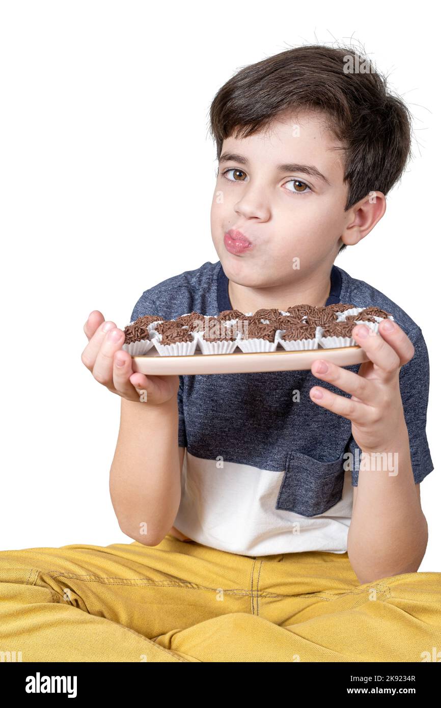 Das 9-jährige Kind hält ein Tablett mit mehreren brasilianischen Fudge-Bällen und puckert ihre Lippen. Stockfoto