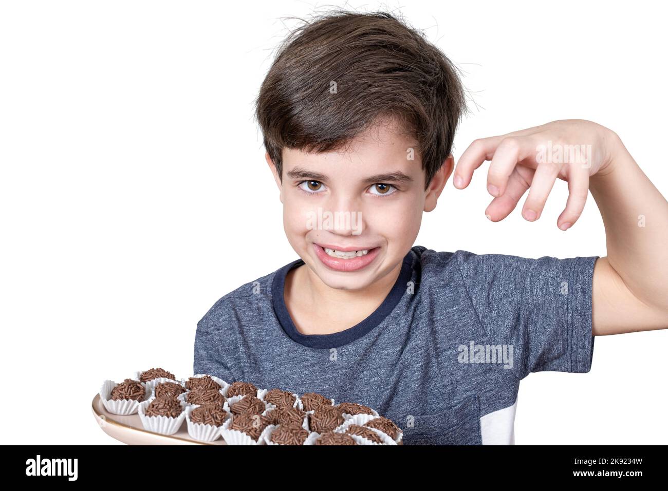 9-Jähriger hält ein Tablett mit mehreren brasilianischen Fudge-Kugeln, bereit, sie zu fangen. Stockfoto