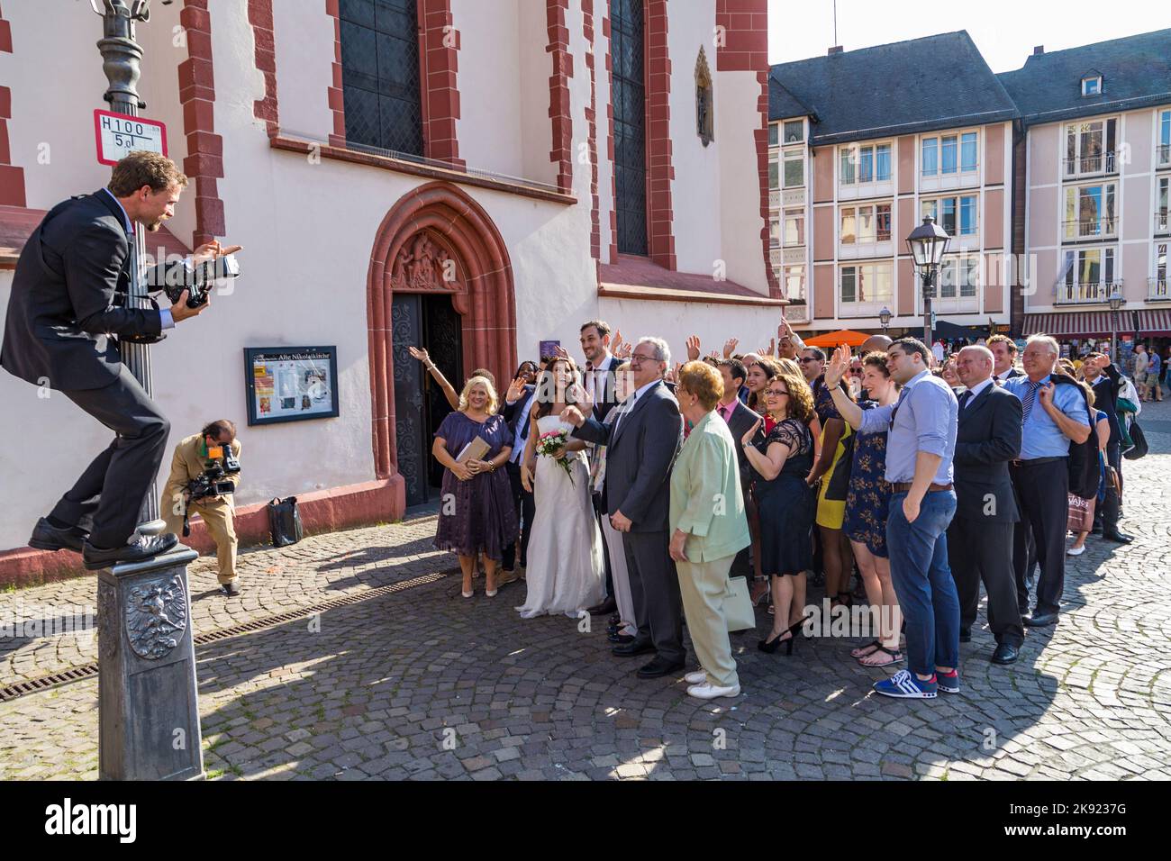 FRANKFURT, DEUTSCHLAND - 9. AUG 2014: Ehepaar mit Familie posiert für ein Hochzeitsfoto vor der Frankfurter Nicolai-Kirche. Stockfoto