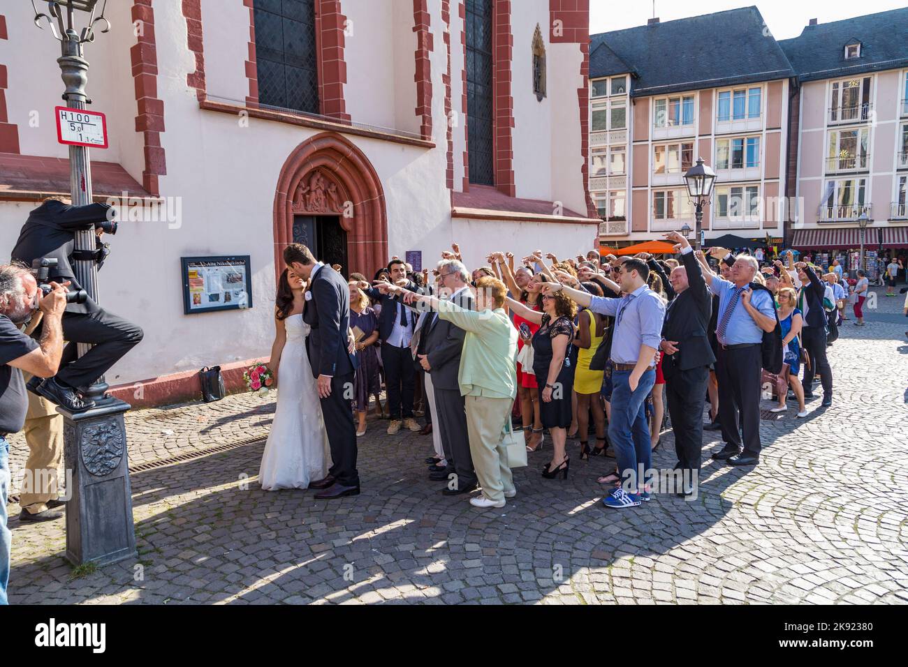 FRANKFURT, DEUTSCHLAND - 9. AUG 2014: Ehepaar mit Familie posiert für ein Hochzeitsfoto vor der Frankfurter Nicolai-Kirche. Stockfoto