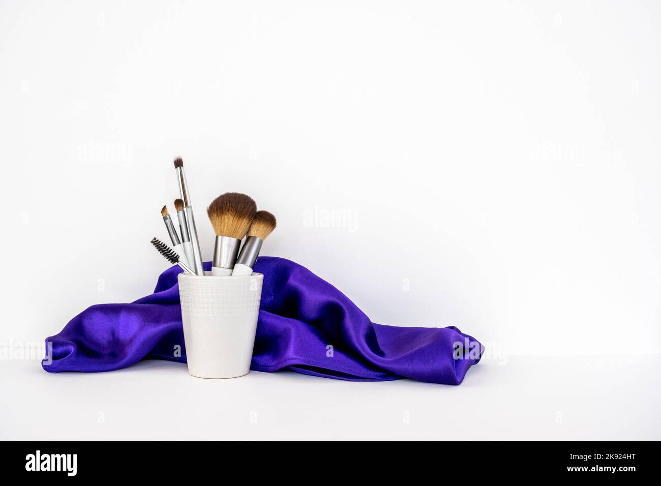 Minimal Concept Make-up Pinsel und lila Seidentuch. Stockfoto