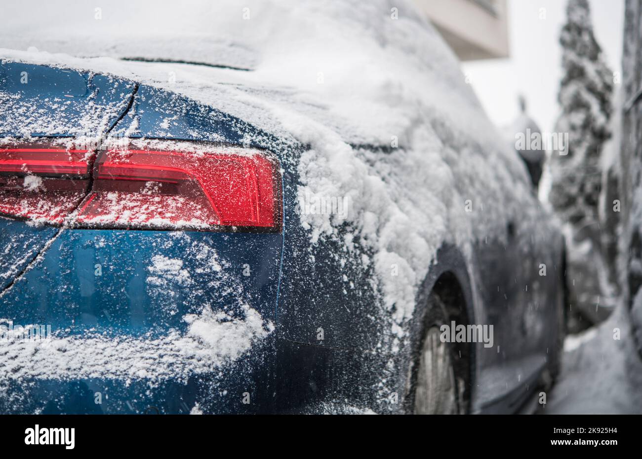 Nahaufnahme des blauen Fahrzeugs mit Schnee bedeckt, der im Winter von einem Fahrer ohne Garage draußen geparkt wurde. Parkprobleme In Der Kalten Jahreszeit. Stockfoto