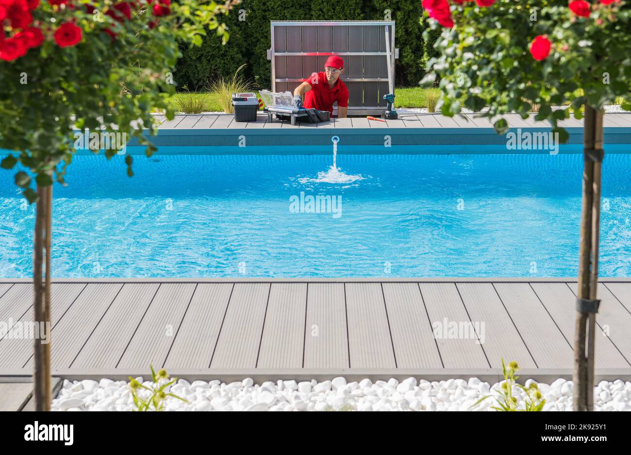 Professioneller Techniker, der saisonale Wartungsarbeiten an Außenschwimmbad-Reinigungsfiltern und das Heizungssystem überprüft. Wunderschön Angelegt Stockfoto