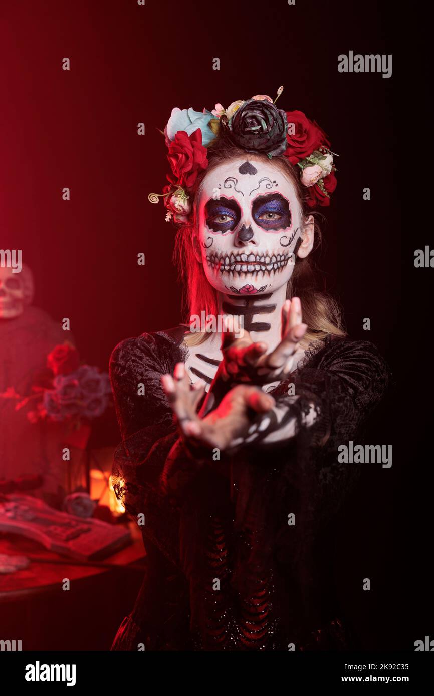 Gruselige Horror-Frau, die mit der Hand greift und versucht, Opfer im Studio zu locken und zu verführen. Flirty santa muerte Modell mit mexikanischen rituellen Kostüm auf Feiertagsfeier, Tag der Toten Mythos. Stockfoto
