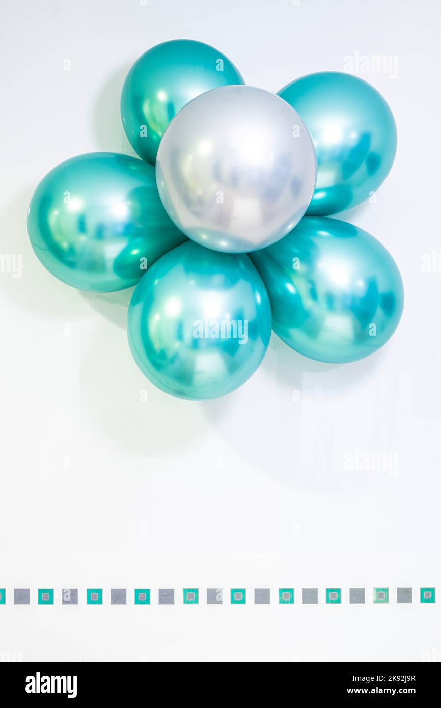 Blume aus Heliumballons in metallischen Farben grün und silber, auf weißem Hintergrund, Kopierraum, grüne und silberne Quadrate Voliere, vertikal Stockfoto