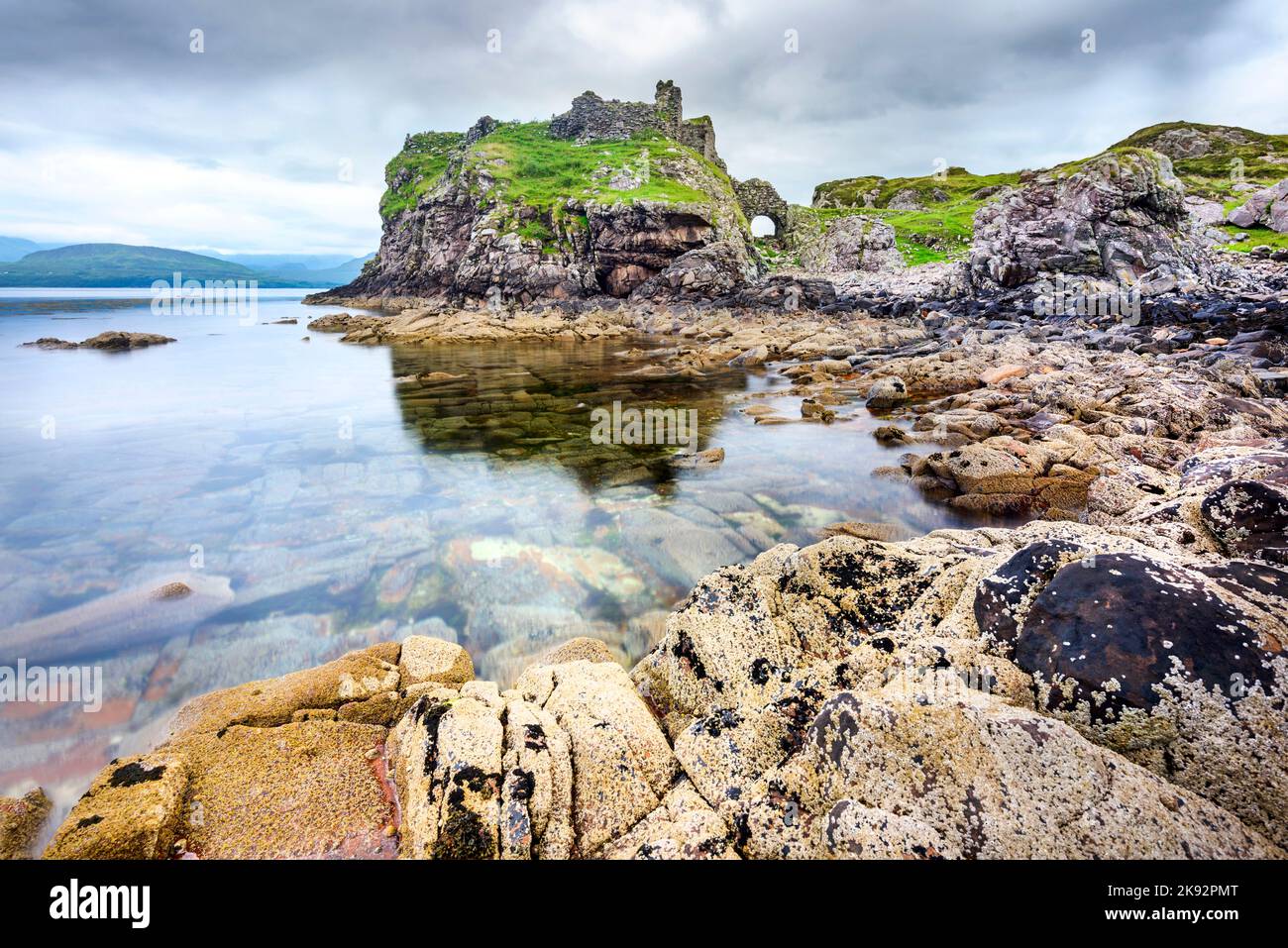 Neben dem ruhigen Wasser bei Ebbe, im Hochsommer, Reste eines historischen schottischen Schlosses, überblicken die glatte Oberfläche des Lochs und viele Boule Stockfoto
