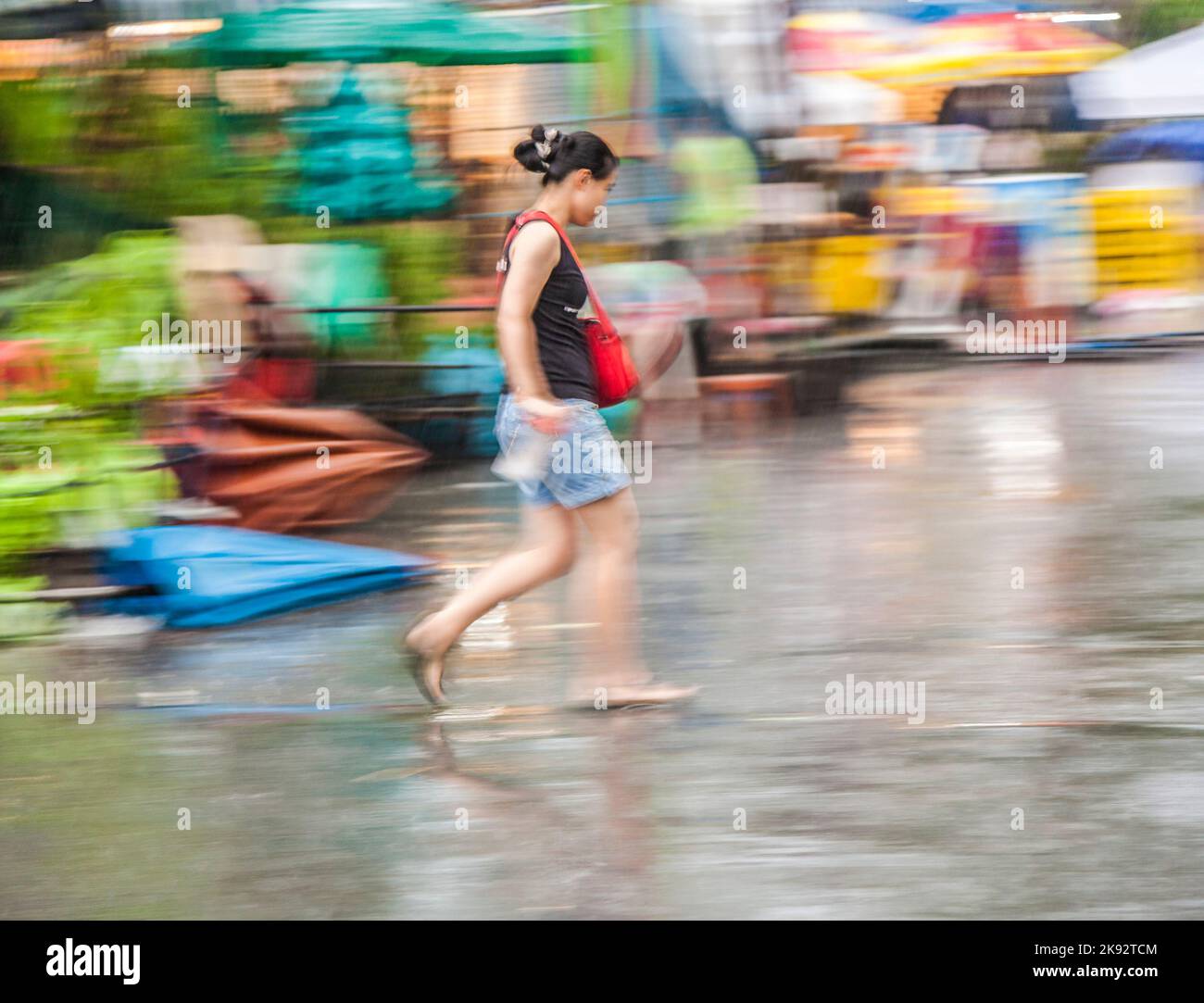 BANGKOK, THAILAND - 10. MAI 2009: Frau in unscharfer Bewegung auf dem Chatuchak Wochenend-Markt in Regen Bangkok, Thailand. Es ist der größte Markt in Tha Stockfoto
