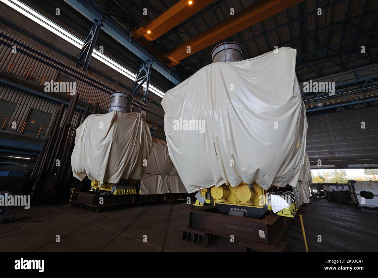 PRODUKTION - 19. Oktober 2022, Mecklenburg-Vorpommern, Warnemünde: In der Schiffbauhalle des Marinearsenals, ehemals MV Werften, warten Schiffsmotoren für das ursprünglich geplante Kreuzschiff 'Global 2' auf Käufer. Insgesamt müssen 17.500 Tonnen Stahlschrott verarbeitet werden, bis der Standort für die zukünftige Nutzung vollständig bereit ist. Im neuen Marinestützpunkt sollen künftig vier Schiffe pro Jahr repariert werden und auch Aufträge im Wert von Millionen an den Privatsektor vergeben werden. Foto: Bernd Wüstneck/dpa Stockfoto