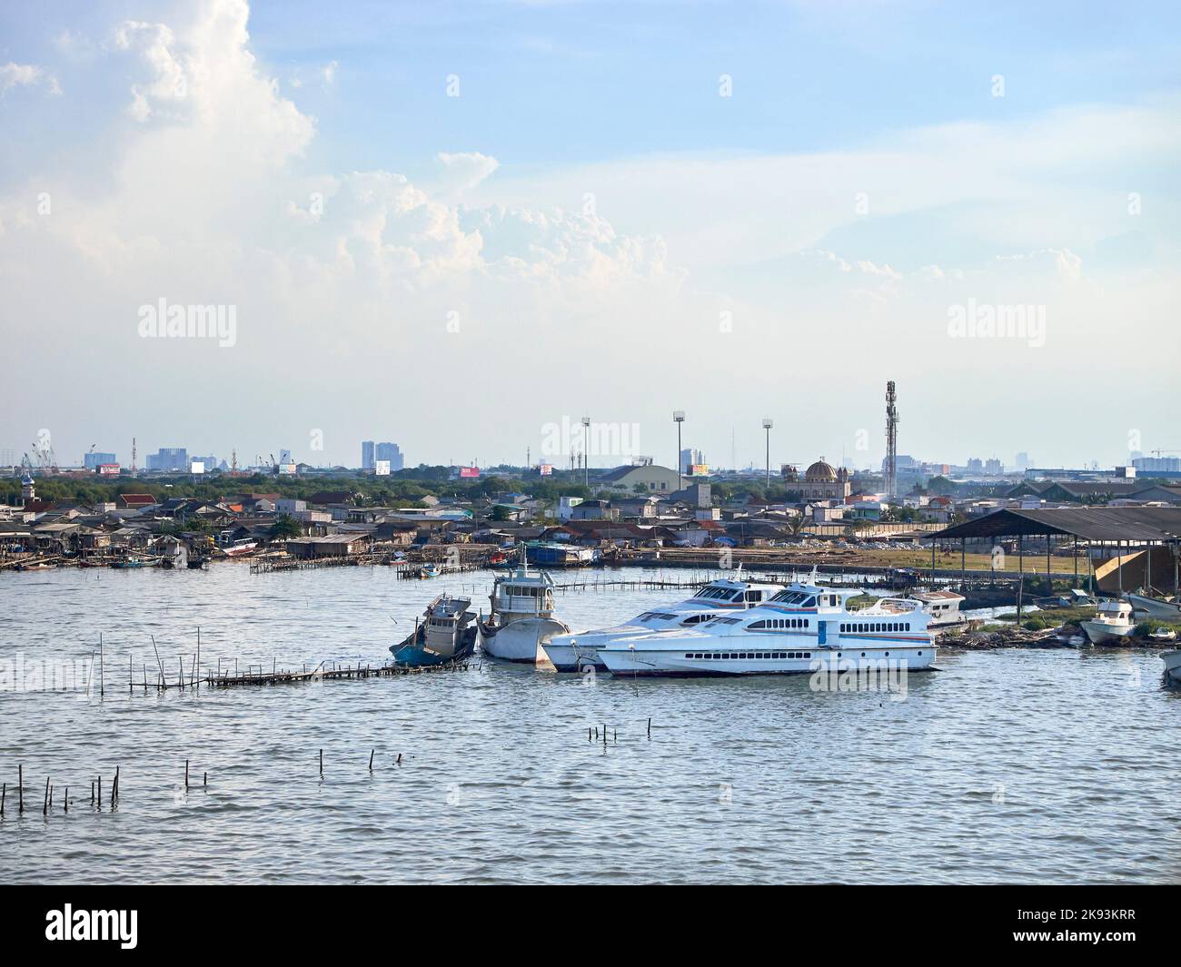 Boote, die auf dem wiedergewonnenen Strandgebiet vor dem Hintergrund von Fischersiedlungen auf Pantai Indah Kapuk, Nord-Jakarta, gelehnt sind Stockfoto