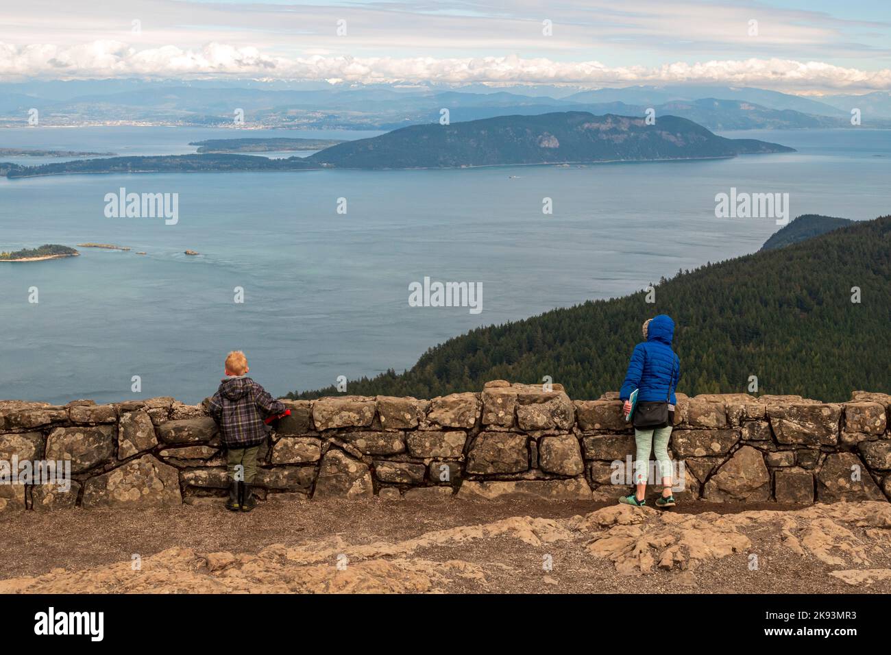 Ein kleiner Junge und ein Mädchen in Wintermänteln bewundern den Blick auf die San Juan Inseln vom Wachturm auf dem Mount Constitution auf der Orcas Island, Washington, Stockfoto