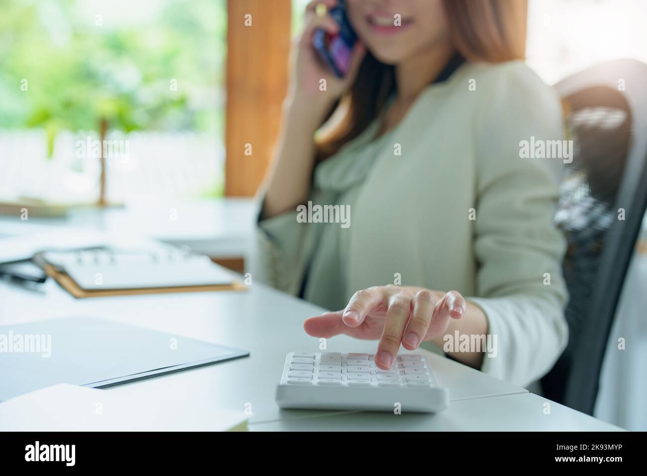 Porträt eines asiatischen Bankmitarbeiters mit einem Finanzbudget-Rechner, Notizblock, Telefon und Computer zur Arbeit Stockfoto