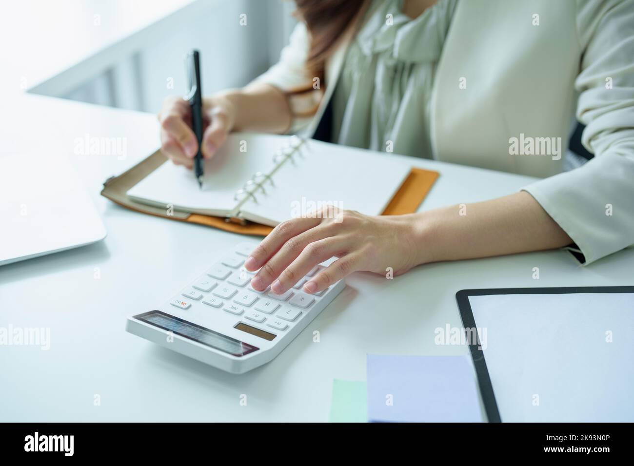 Porträt eines asiatischen Bankmitarbeiters mit einem Finanzbudget-Rechner, Notizblock und Computer zur Arbeit Stockfoto