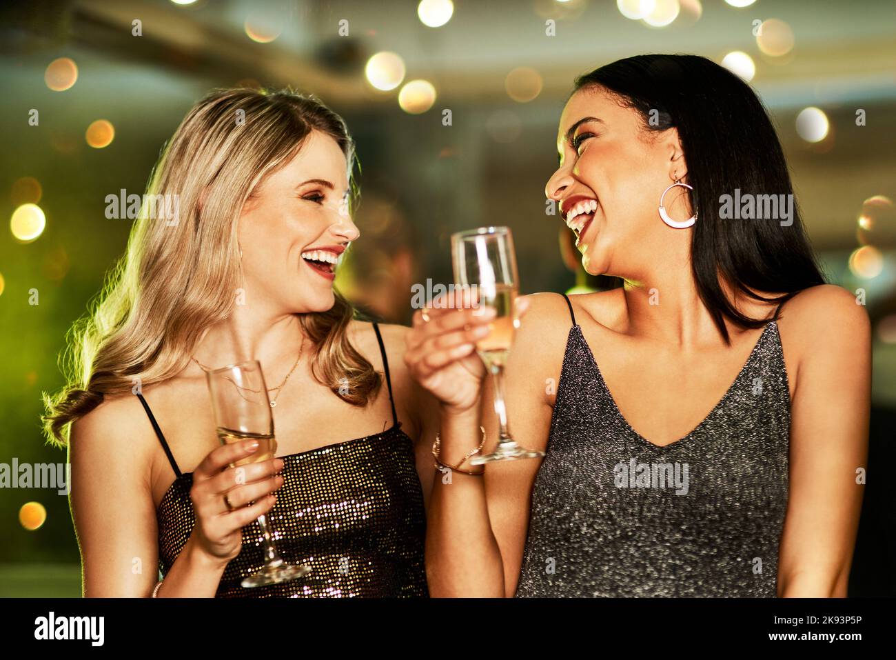 Wir können ewig jung sein. Zwei fröhliche junge Frauen, die abends auf der Tanzfläche eines Clubs einen Drink genießen. Stockfoto