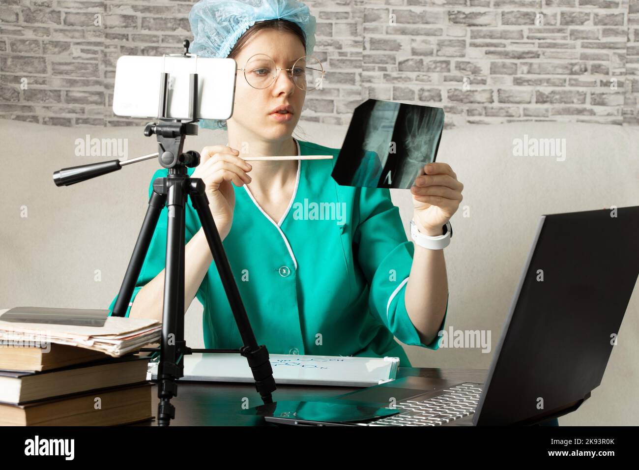 Ein Arzt in einer medizinischen Uniform führt eine Online-Konsultation per Videochat durch und hält eine Röntgenaufnahme in den Händen, eine medizinische Konferenz online Stockfoto