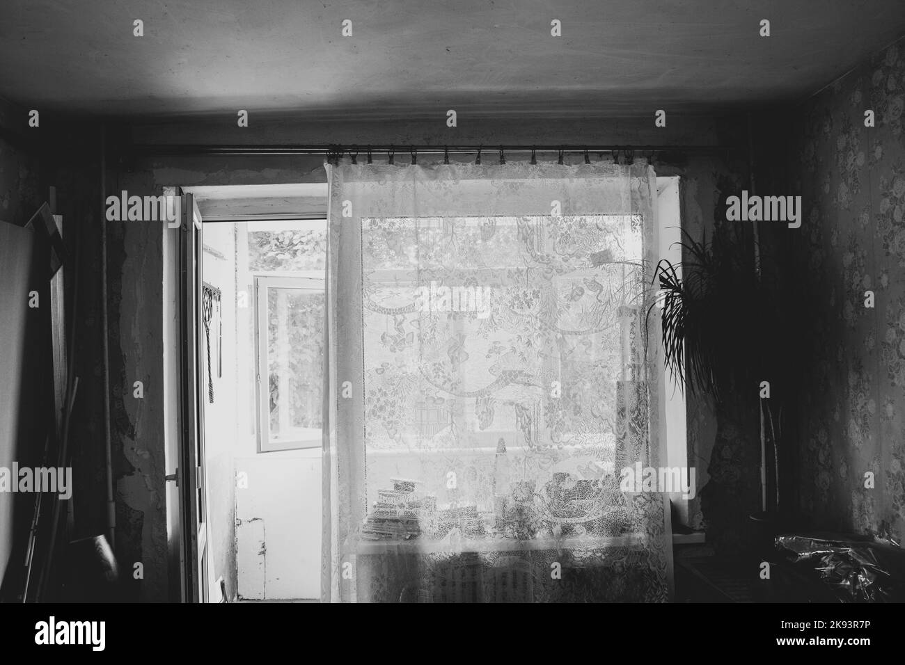 Ein altes Zimmer mit Fenster in einer sowjetischen Wohnung in der Ukraine ohne Renovierung mit leeren Wänden und zerrissenen Tapeten, ein Zimmer vor der Renovierung, ein leeres Stockfoto