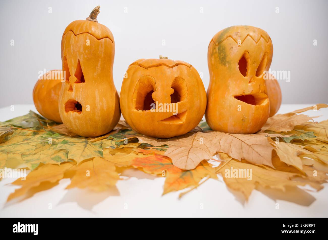 Gruppe von Jack-o-Laterne auf Ahornblättern. Halloween Dekoration auf weißem Hintergrund. Stockfoto