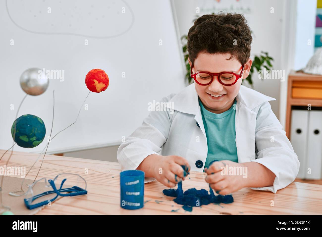 Wir alle wissen, dass ein Chaos immer Spaß macht. Ein entzückender junger Schuljunge spielt und experimentiert mit Schleim in der Wissenschaft Klasse in der Schule. Stockfoto