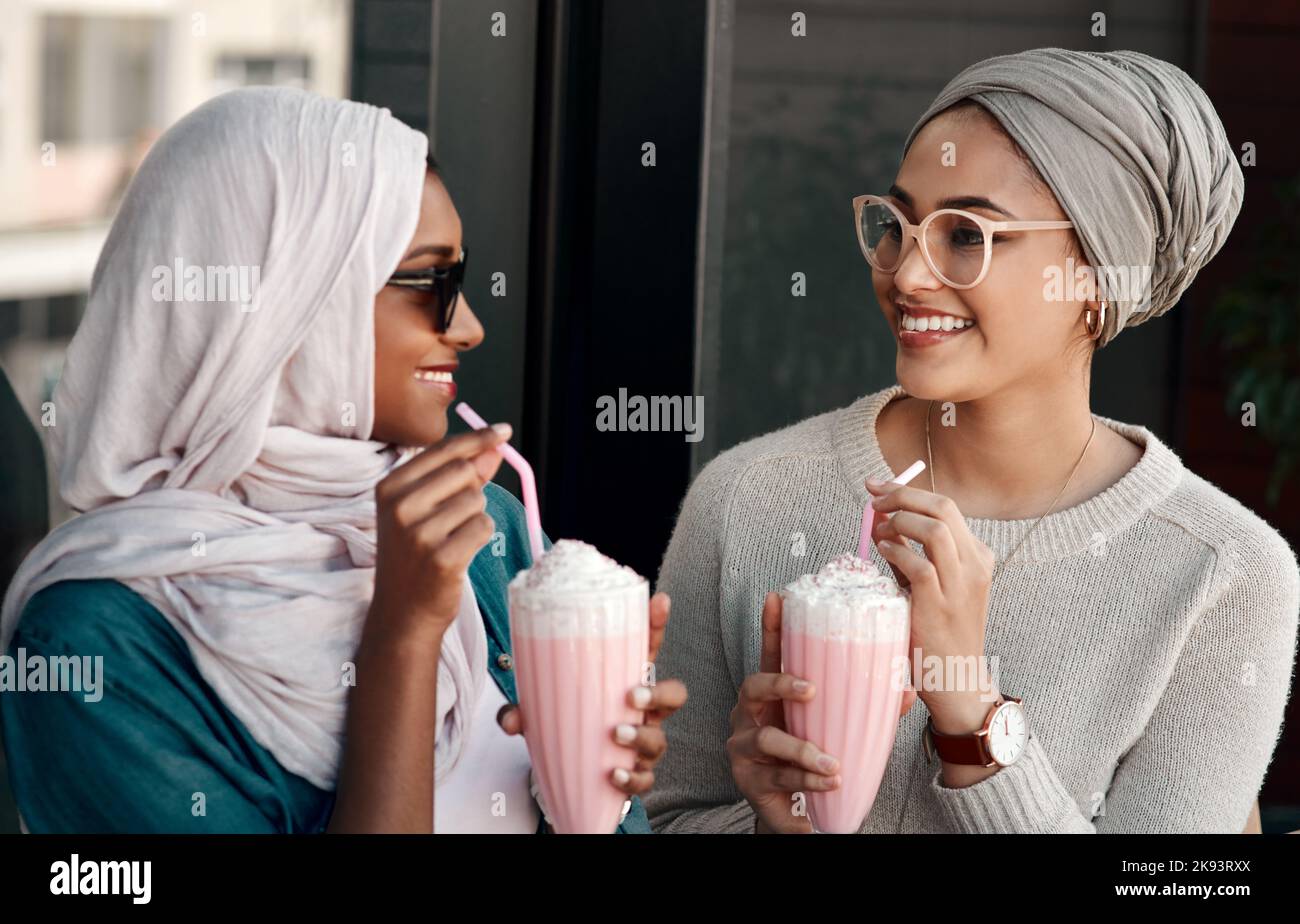 Ich bin froh, dass wir endlich Zeit hatten, dies zu tun. Zwei liebevolle junge Freundinnen, die in Hijab gekleidet in einem Café Milchshakes zusammen hatten. Stockfoto
