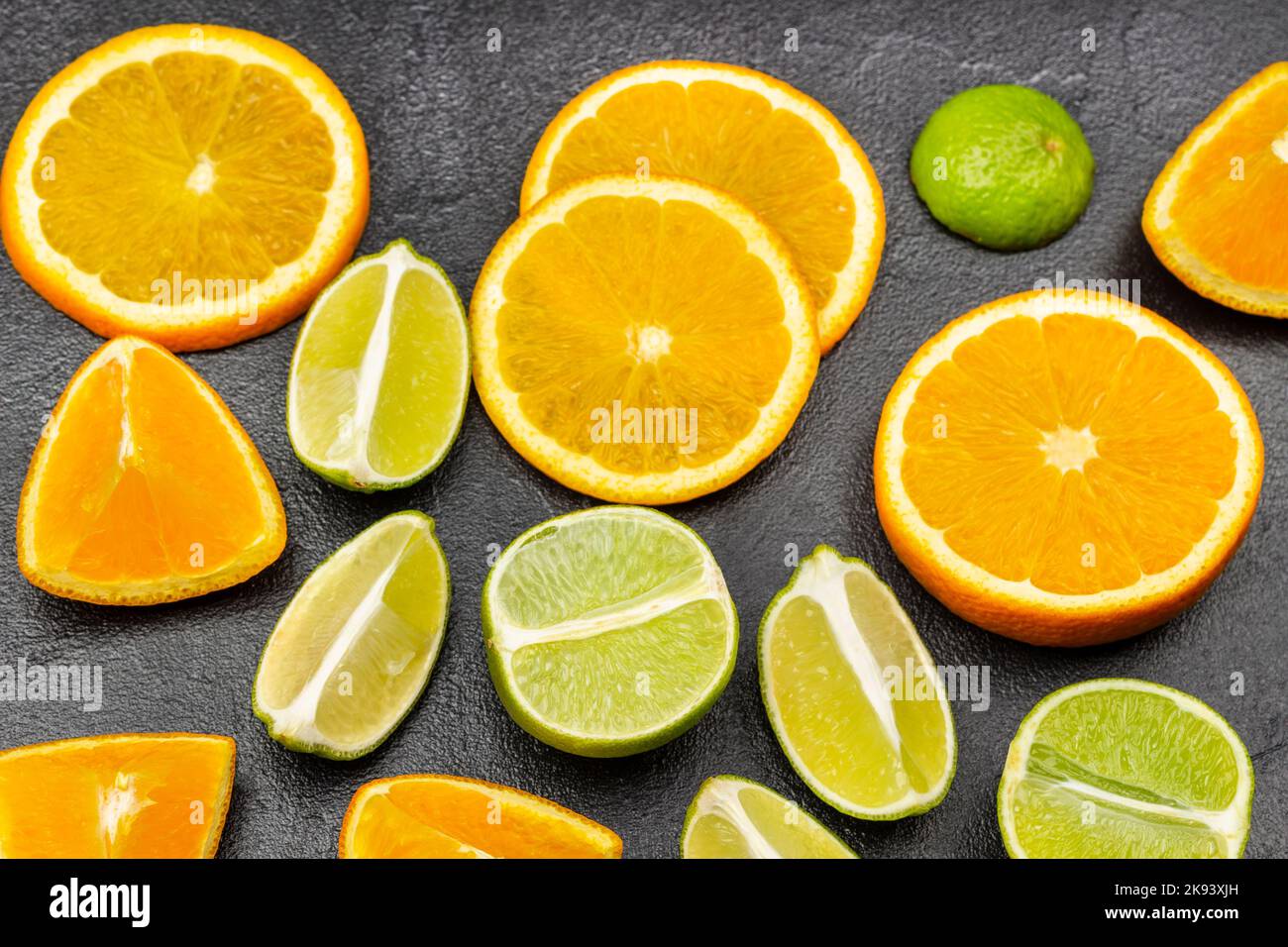 Natürliche Quelle der Stärkung der Immunität. Scheiben aus Orange und Limette auf dem Tisch. Flach liegend. Schwarzer Hintergrund. Stockfoto