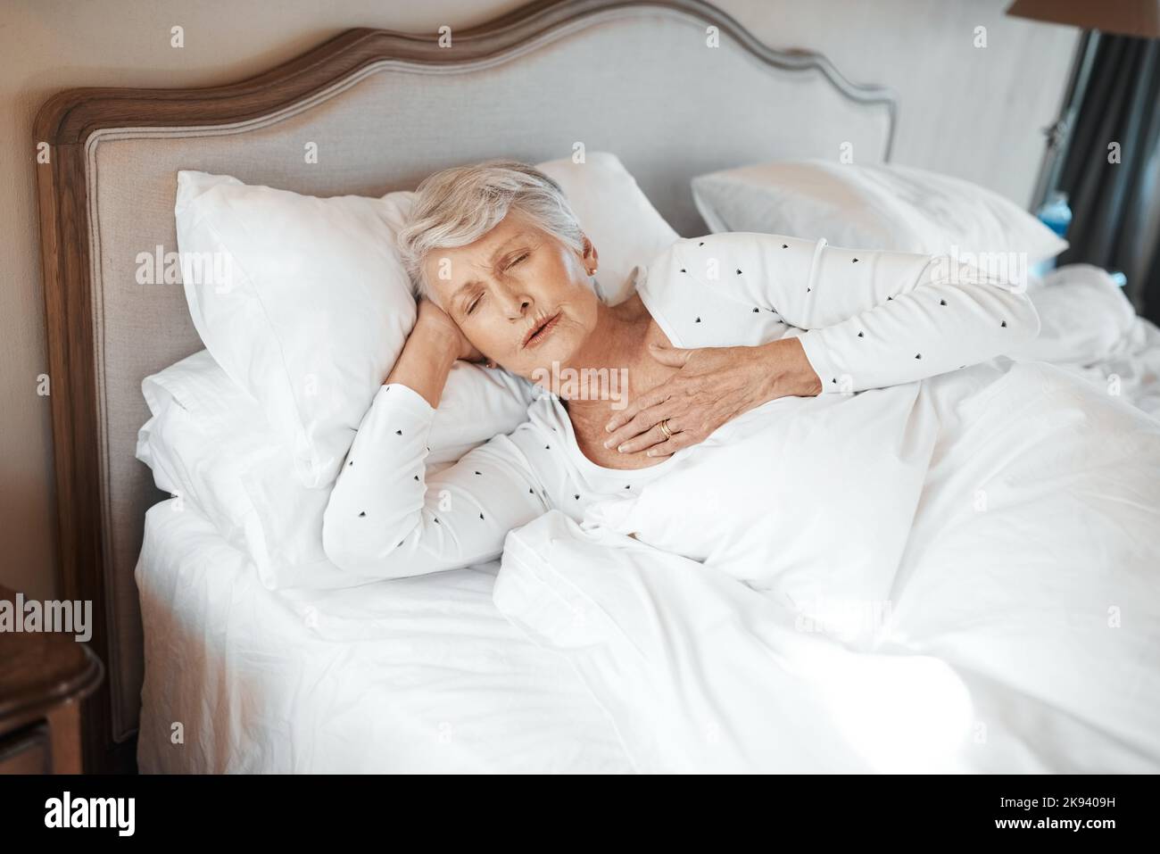 Als letztes haben Sie Ihr Herz überprüft. Eine ältere Frau, die Brustschmerzen im Bett in einem Pflegeheim hat. Stockfoto