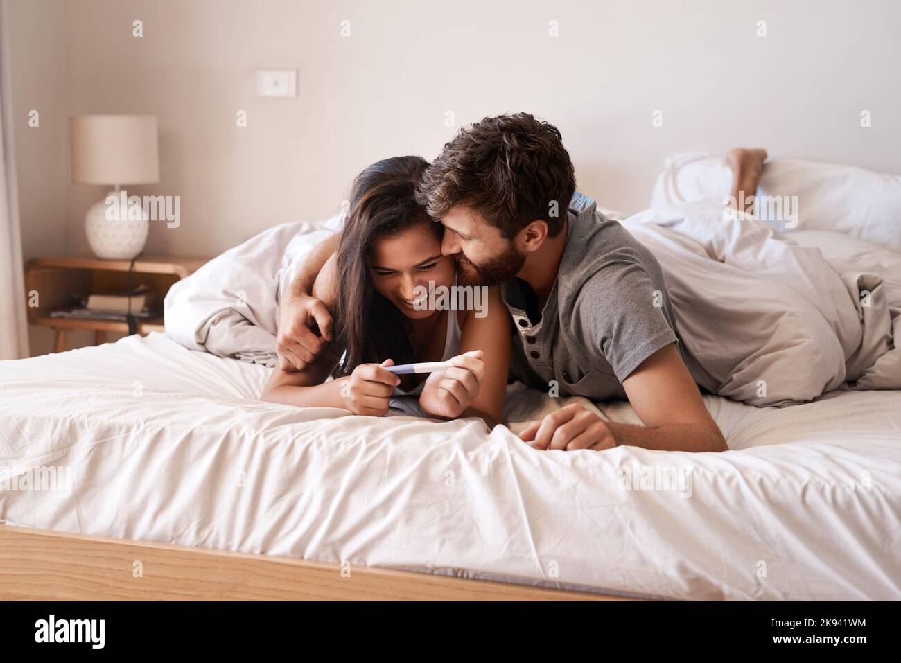 Kann uns jemand bald Mama und Papa nennen? Ein glückliches junges Paar, das zu Hause einen Schwangerschaftstest macht. Stockfoto