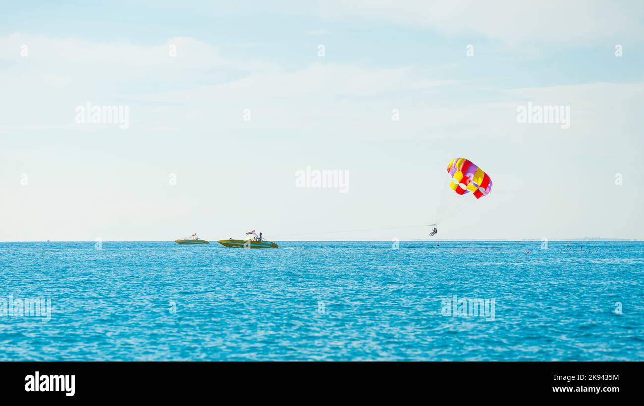 Herrliche Aussicht auf den bunten Parasailflügel, der von einem Boot gezogen wird, im strahlend blauen Meer, Alanya, Türkei. Hochwertige Fotos Stockfoto