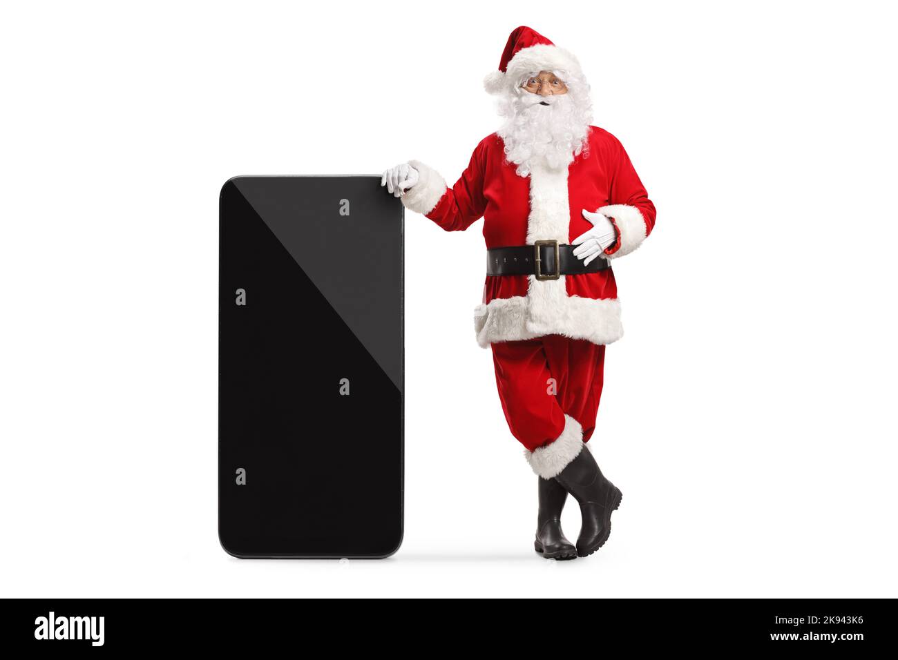 Der weihnachtsmann lehnt sich auf ein großes Mobiltelefon, das auf weißem Hintergrund isoliert ist Stockfoto