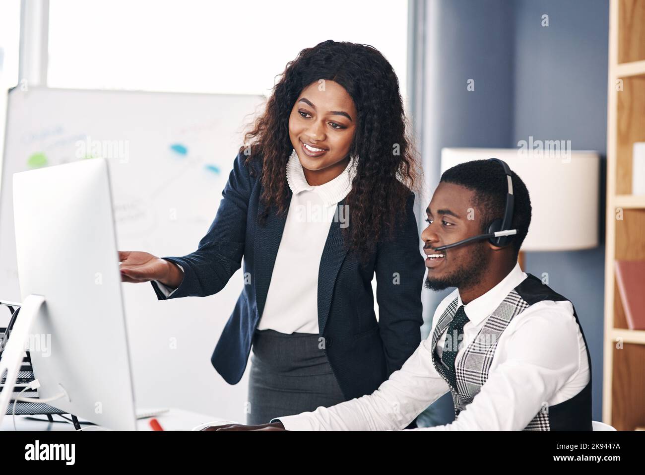 Weitergabe ihrer Kenntnisse in der Kundenbetreuung. Eine junge Frau hilft ihrem Kollegen in einem Callcenter. Stockfoto