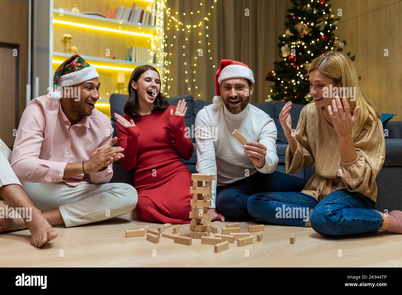 Neujahr Party, verschiedene Freunde zu Hause auf dem Boden spielen Spiel, Männer und Frauen lächeln und glücklich zusammen für weihnachten verbringen Zeit. Stockfoto