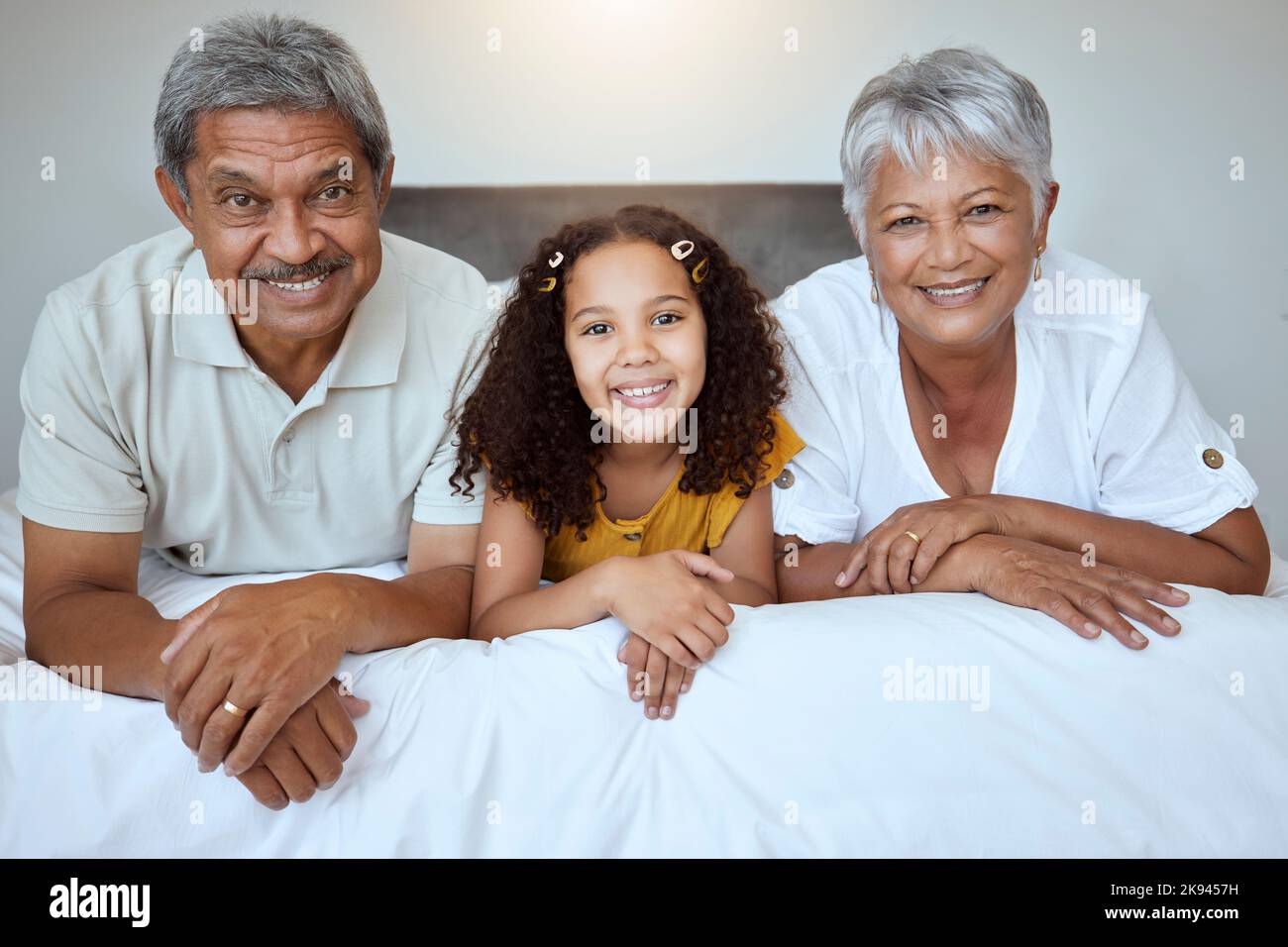 Glücklich, Großeltern und Kind liegen auf dem Bett mit einem Lächeln für die Familie zu verbinden, Ruhestand und zu Hause entspannen. Porträt von Mädchen, Oma und Opa Stockfoto